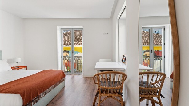 Une chambre d’hôtel avec un lit, une petite table, une chaise et un balcon avec vue.