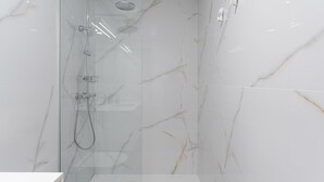 Une salle de bain moderne dotée d’une douche à parois de verre, de murs en marbre et d’un design minimaliste.