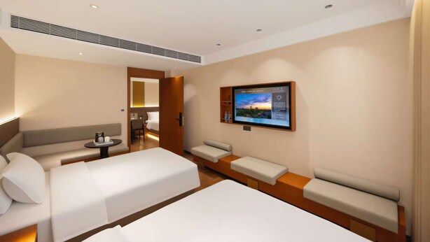 A hotel room with two beds, a sofa, a TV, and a desk. - Gulou Lanting Hotel  (Beijing)