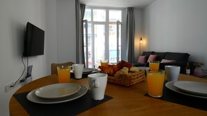A dining area with a table set for breakfast, including plates, cups, and a basket of bread.