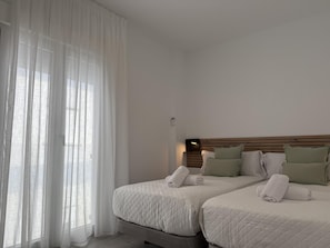 A hotel room with two beds, white bedding, a wooden headboard, and sheer curtains. - ONE BEDROOM FLAT ...... (MALAGA)