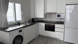 A modern kitchen with white cabinetry, a built-in washing machine, a dishwasher, a microwave, and a refrigerator. - ONE BEDROOM FLAT ...... (MALAGA)