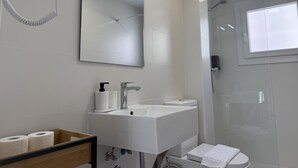 Un baño moderno con un espejo grande, un lavabo blanco y un secador de pelo de mano.