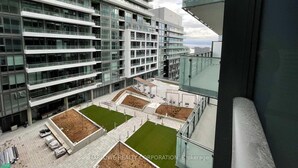 A modern high-rise building with multiple balconies and a rooftop garden area.