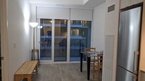 A spacious kitchen with a large refrigerator, a dining table with chairs, a bench, and a floor lamp.