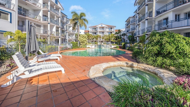 Un resort con piscina, sillas de descanso y un jardín bien cuidado.