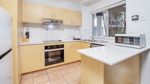 Una cocina con armarios de madera, horno integrado, microondas y ventana con vistas.