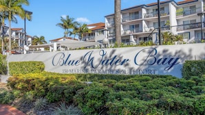 Señal de Blue Water Bay, en el número 150 de Marine Parade, Southport, con vista al edificio y la vegetación circundante.