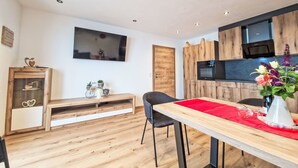 A modern kitchen with wooden cabinets, a built-in oven, and a flat-screen TV.