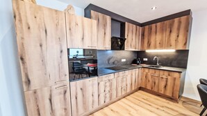 A modern kitchen with wooden cabinets, a black countertop, and a built-in oven.
