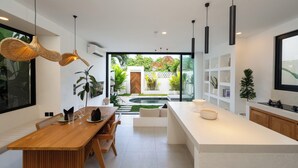 Una cocina moderna con una isla central, mesa de comedor de madera e iluminación colgante.