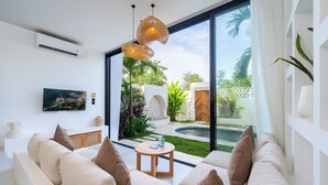 Una sala de estar moderna con un amplio ventanal, un sofá, una mesita y una lámpara colgante.