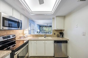 A modern kitchen with a skylight, stainless steel appliances, and a view to the outside.