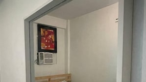 A small, single-bed room with a wooden headboard, a teal bedspread, and a single air conditioning unit mounted on the wall. - D and A Transient Inn Taguig (Taguig)
