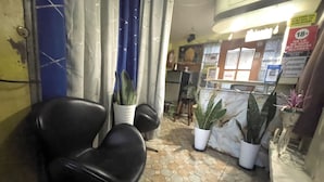 A small, enclosed waiting area with a tiled floor, several potted plants, and a black chair. - D and A Transient Inn Taguig (Taguig)