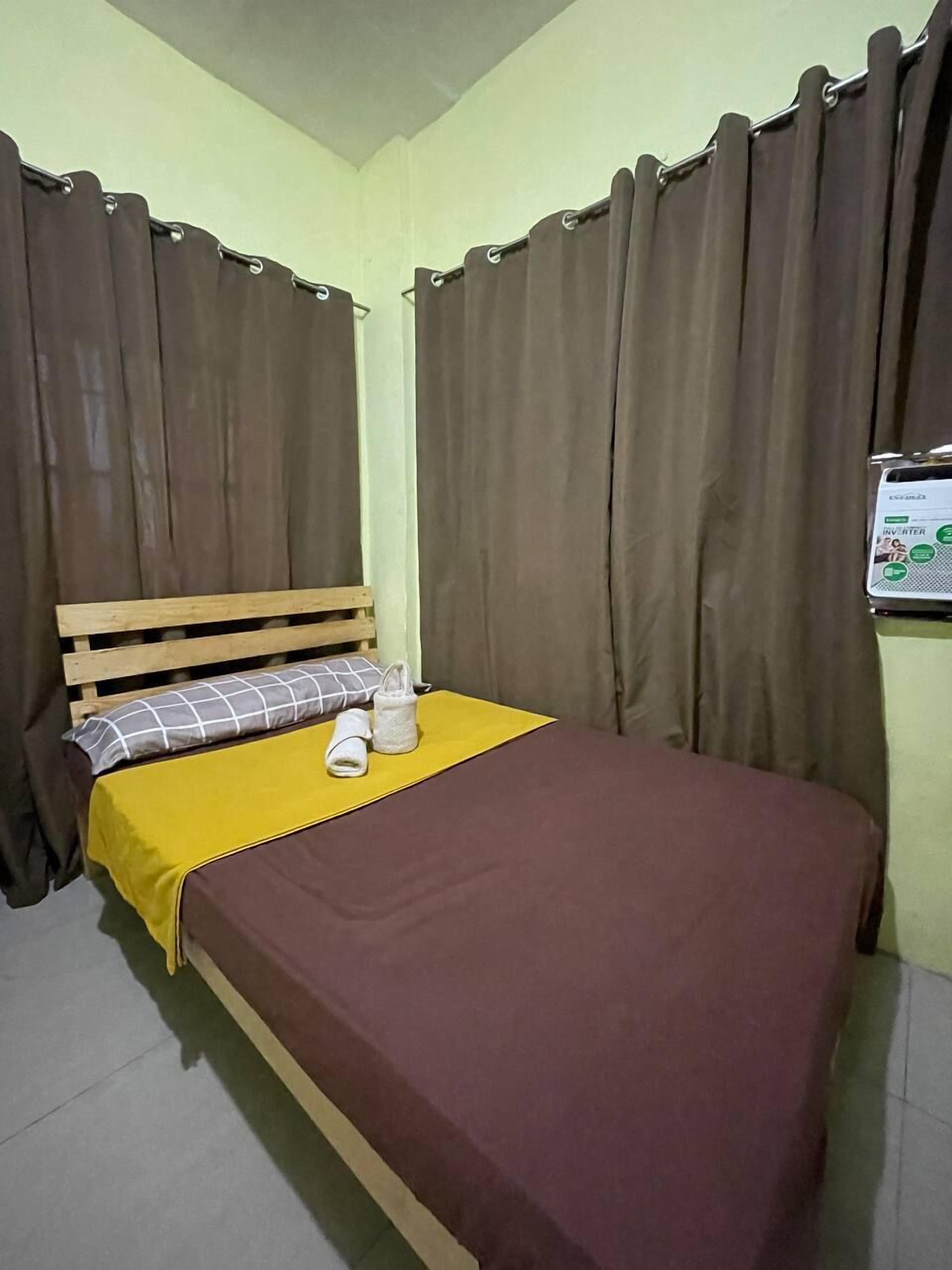 A single bed with a wooden headboard, a yellow blanket, and a brown bedspread.