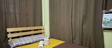 A single bed with a wooden headboard, a yellow blanket, and a brown bedspread.