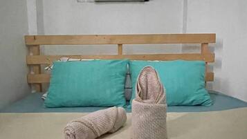 A bed with a wooden headboard, two teal pillows, and a beige blanket.