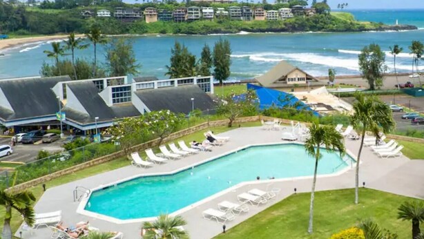 A resort with a large pool, sun loungers, and a view of the ocean. - BRAND NEW REMODELED 2/2 Family Getaway! Walk to Amazing Beach, AC & WiFi (Lihue)