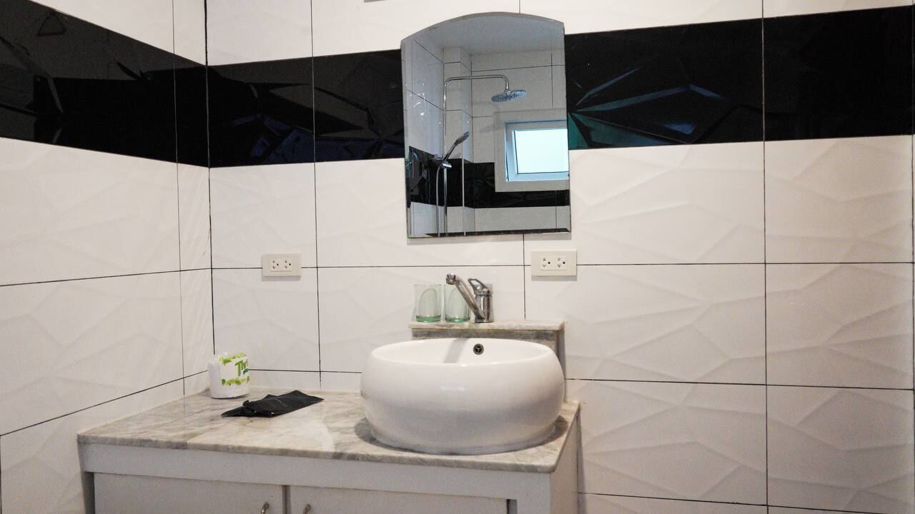 A modern bathroom with a white sink, a mirror, and a shower.