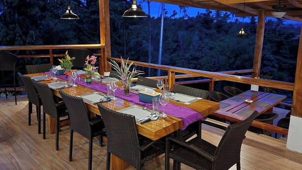 An outdoor dining area with a wooden table set for six, surrounded by wicker chairs. - Tablas Seaview Homestay (Ferrol)
