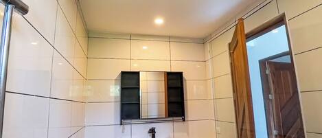Un baño moderno con un lavamanos blanco, un espejo y una ducha con cabezal de ducha manual.
