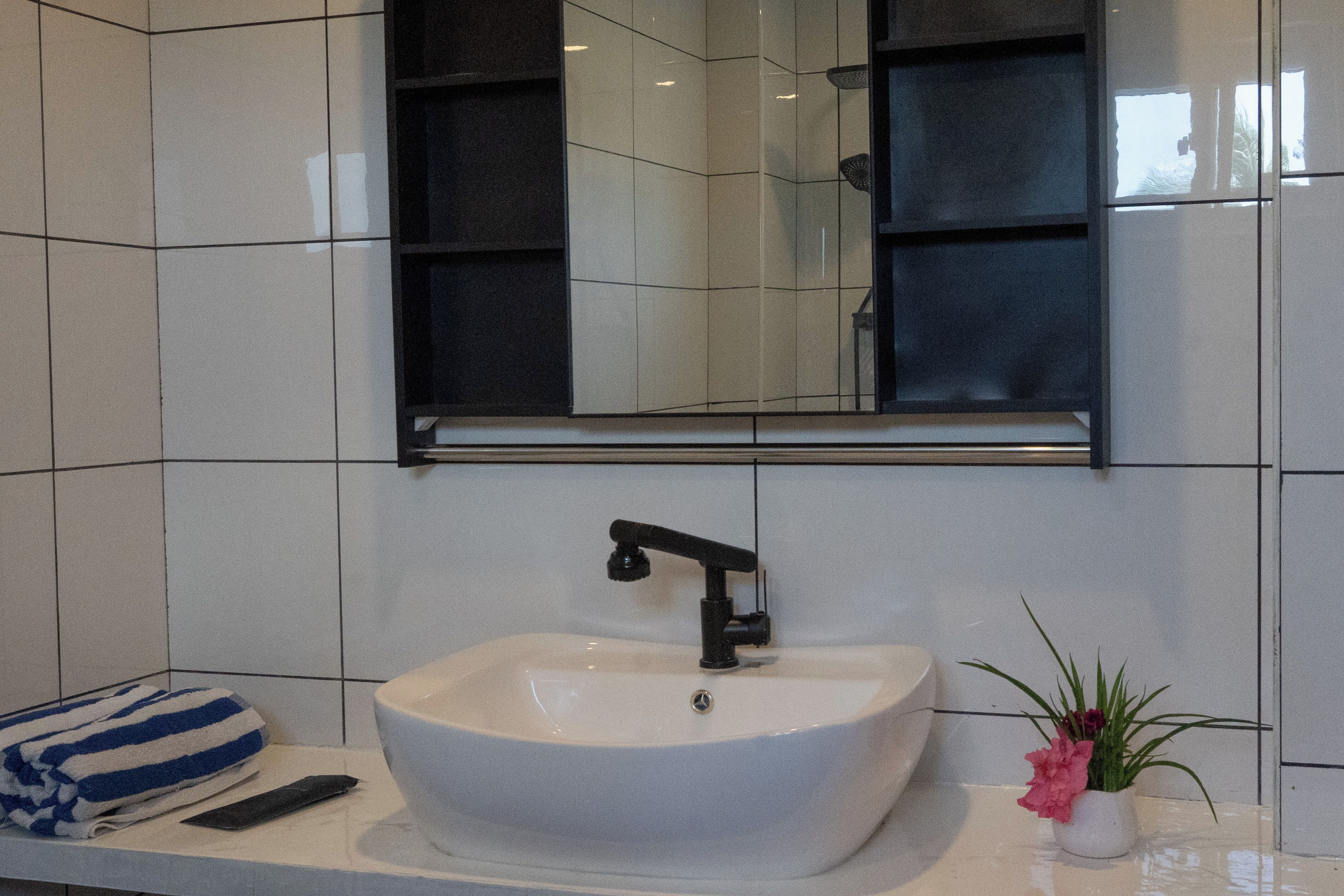 A bathroom with a white sink, a mirror above it, and a towel on the counter.