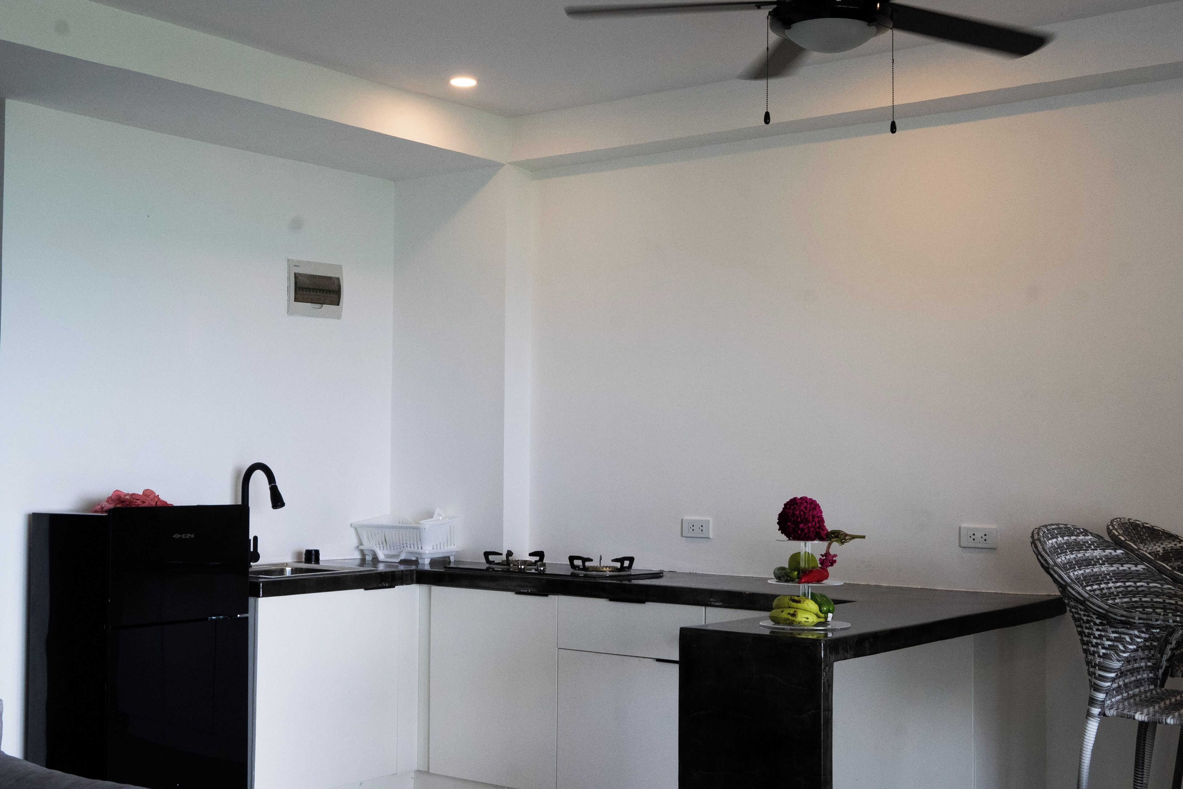 A modern kitchen with a black refrigerator, a gas stove, and a ceiling fan.