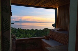 Una habitación con un amplio ventanal que da a una masa de agua tranquila y abundante vegetación.