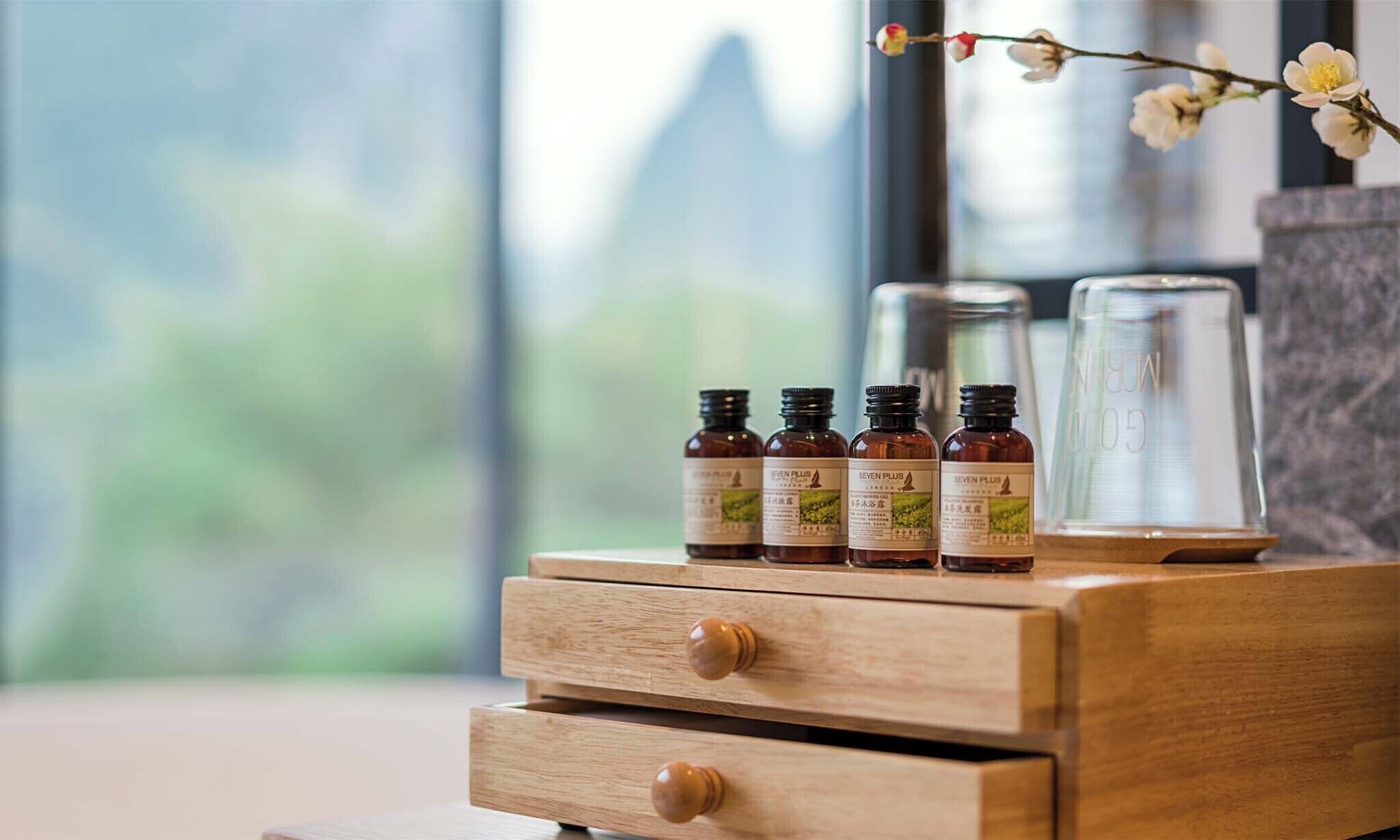 A wooden nightstand with four amber-colored bottles labeled "SEVEN PLUS" and a clear glass container on top.