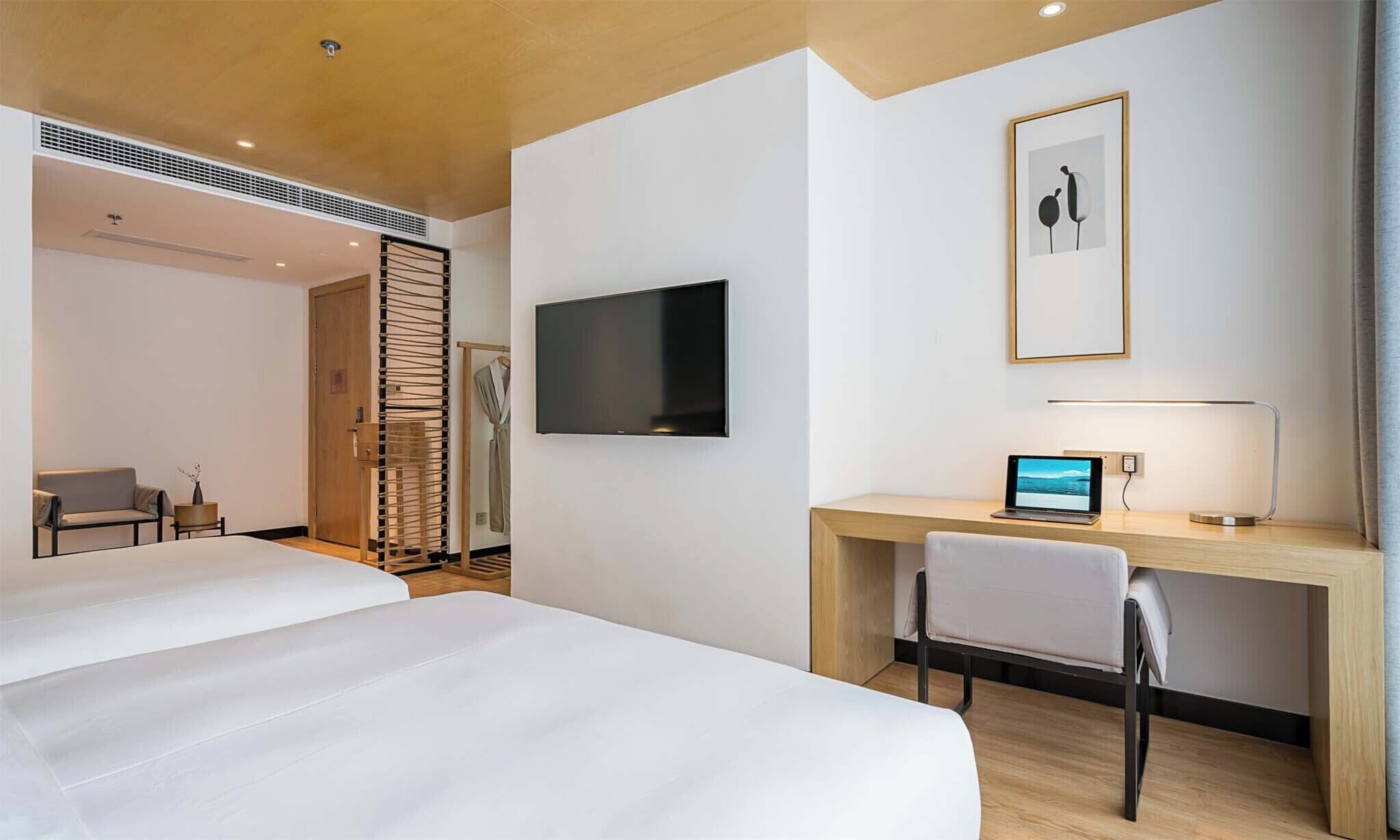 Habitación de hotel con una cama, un escritorio con una computadora portátil, un televisor y una silla.