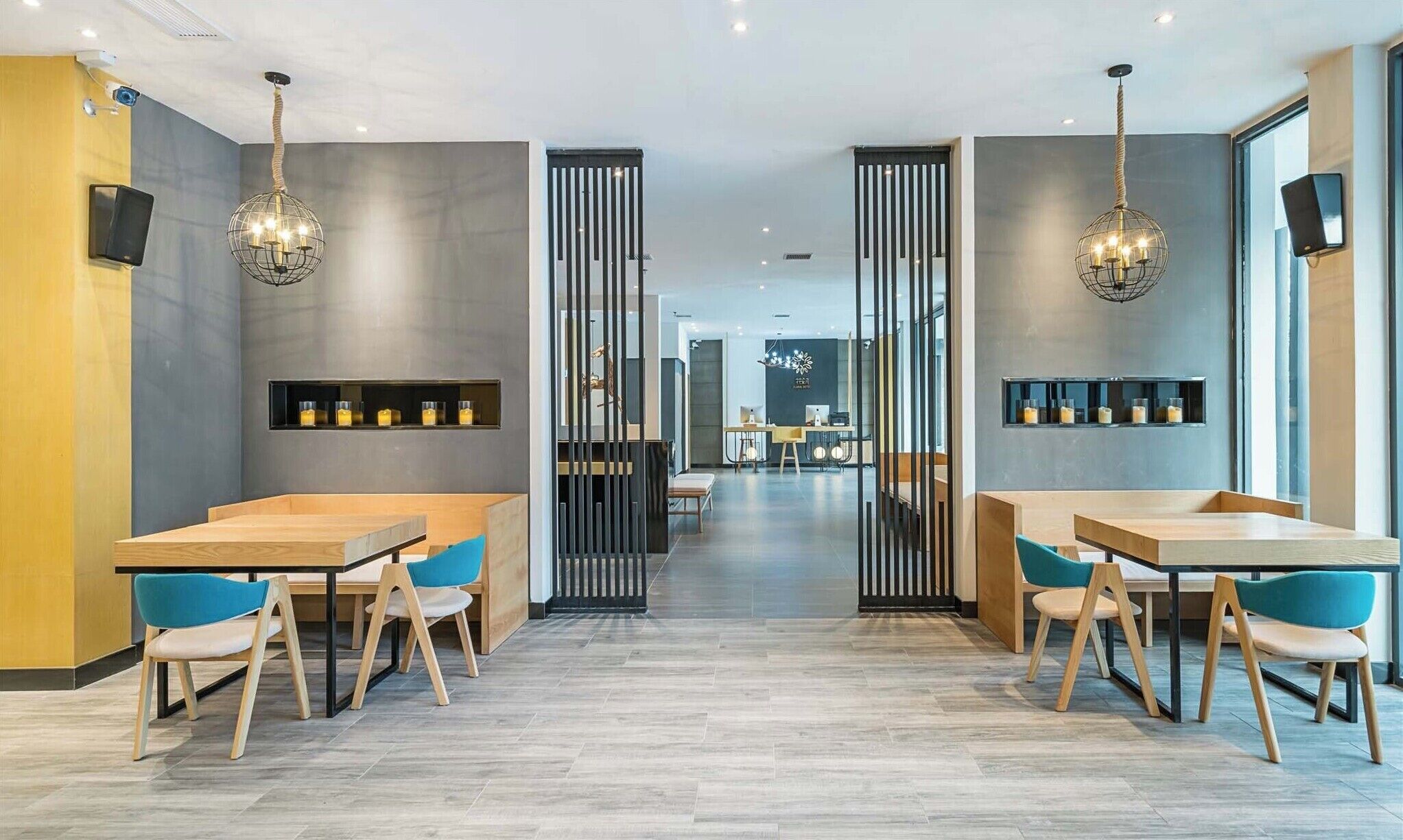 Un restaurante moderno con mesas y sillas de madera, lámparas colgantes y un separador central.