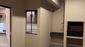Een ruime kamer met betegelde vloer, een raam met uitzicht en een in de muur ingebouwde open haard.
