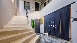 A staircase with beige steps leading to a landing, a black banner with white text, and a modern interior design. - Sauna BBQ with a spectacular view of Mt. Fuji｜Max 20 people｜The No. 10 Mt. (minamitsuru-gun yamanaka-ko hirano)