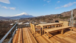 A wooden deck with outdoor furniture overlooking a snowy mountain and a valley. - Sauna BBQ with a spectacular view of Mt. Fuji｜Max 20 people｜The No. 10 Mt. (minamitsuru-gun yamanaka-ko hirano)