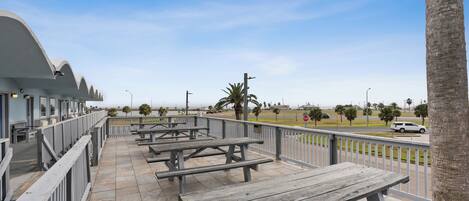 An outdoor patio area with picnic tables and a railing overlooking a street.