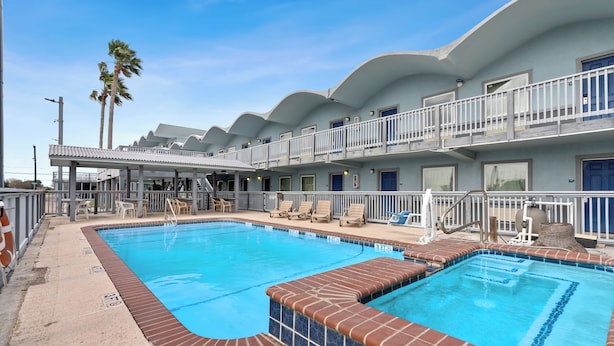 A hotel with a swimming pool, multiple balconies, and a covered outdoor seating area. - First level• Pool* Beach, Festival Grounds+ (Rockport)