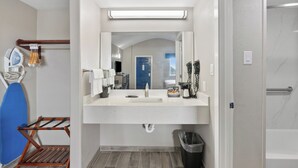 A modern bathroom with a white sink, mirror, and towel rack. There is a shower area visible through the door. - First level• Pool* Beach, Festival Grounds+ (Rockport)