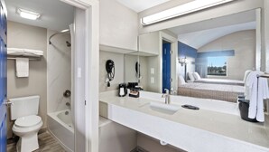 Ein modernes Badezimmer mit Badewanne, Toilette und einem großen Spiegel.