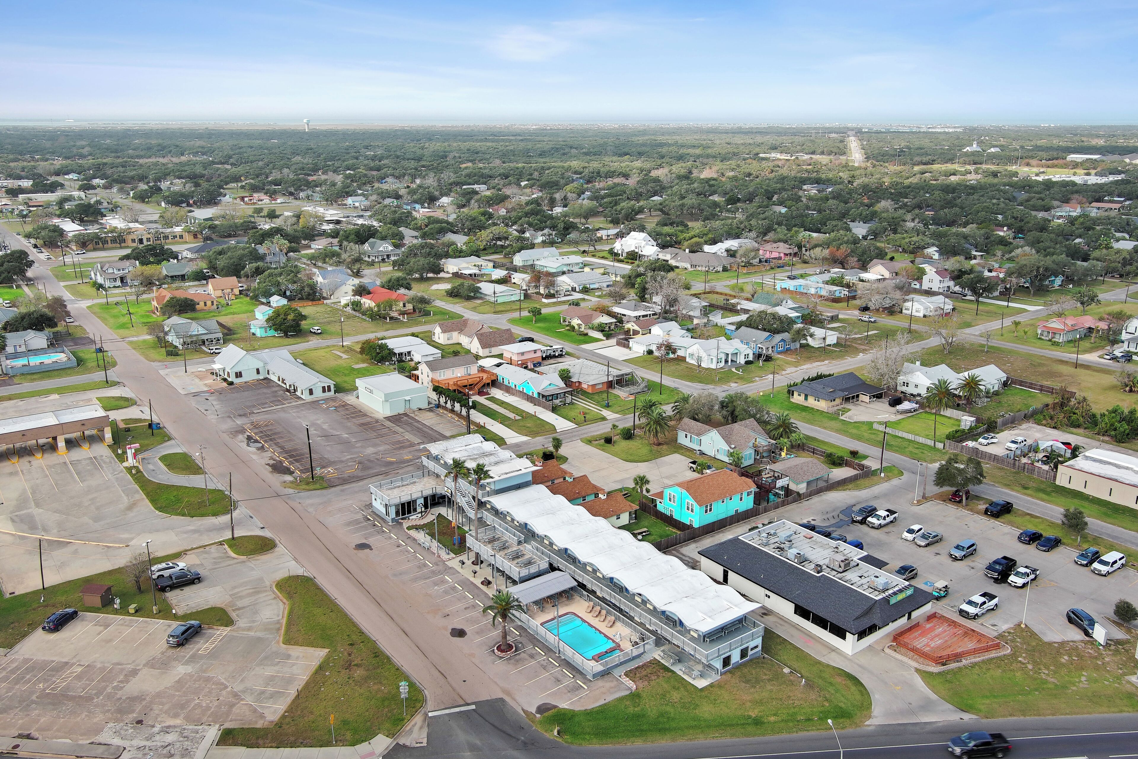 An aerial view of a residential area with houses, a swimming pool, and a parking lot.