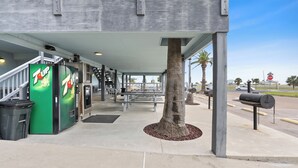 Una tienda 7UP con entrada techada, mesas al aire libre y una palmera.