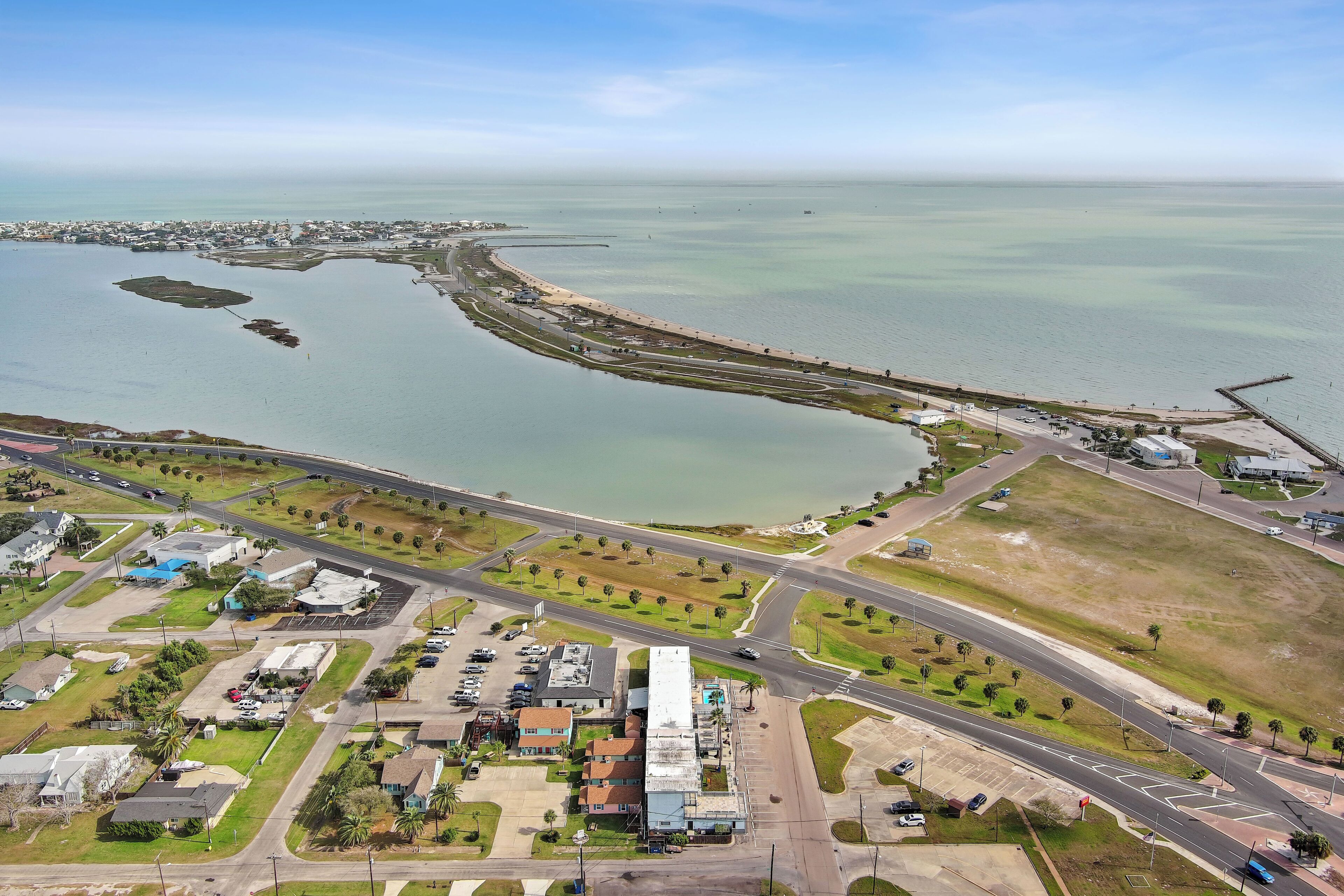 An aerial view of a coastal area with a marina, roads, and residential buildings.