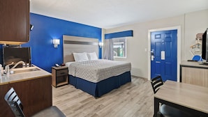 A hotel room with a bed, a desk, a chair, a sink, and a door. - 2nd level pool front • Kitchen • Walk to Beach (Rockport)