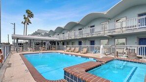 A hotel with a swimming pool, multiple balconies, and a covered outdoor seating area. - Across from festival grounds & blue wave beach ADA (Rockport)