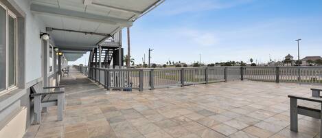 A covered outdoor area with tiled flooring, benches, and a railing.