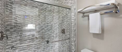 Un baño moderno con ducha de vidrio, inodoro blanco y perchero para toallas.