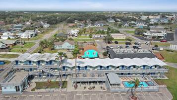 A motel with a pool, multiple rooms, and a parking lot.