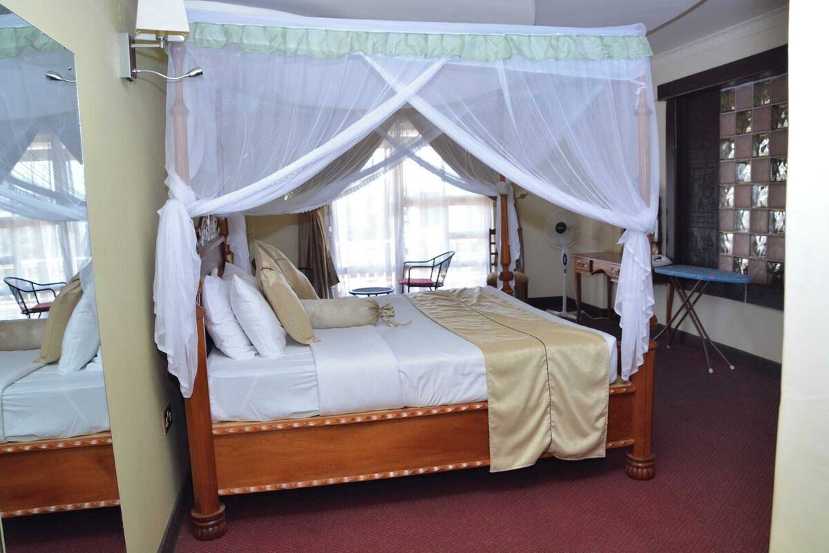 A four-poster bed with a canopy, a wooden headboard, and a red carpeted floor.