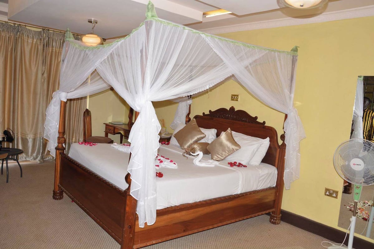 A four-poster bed with a canopy, a bedside table, and a fan.