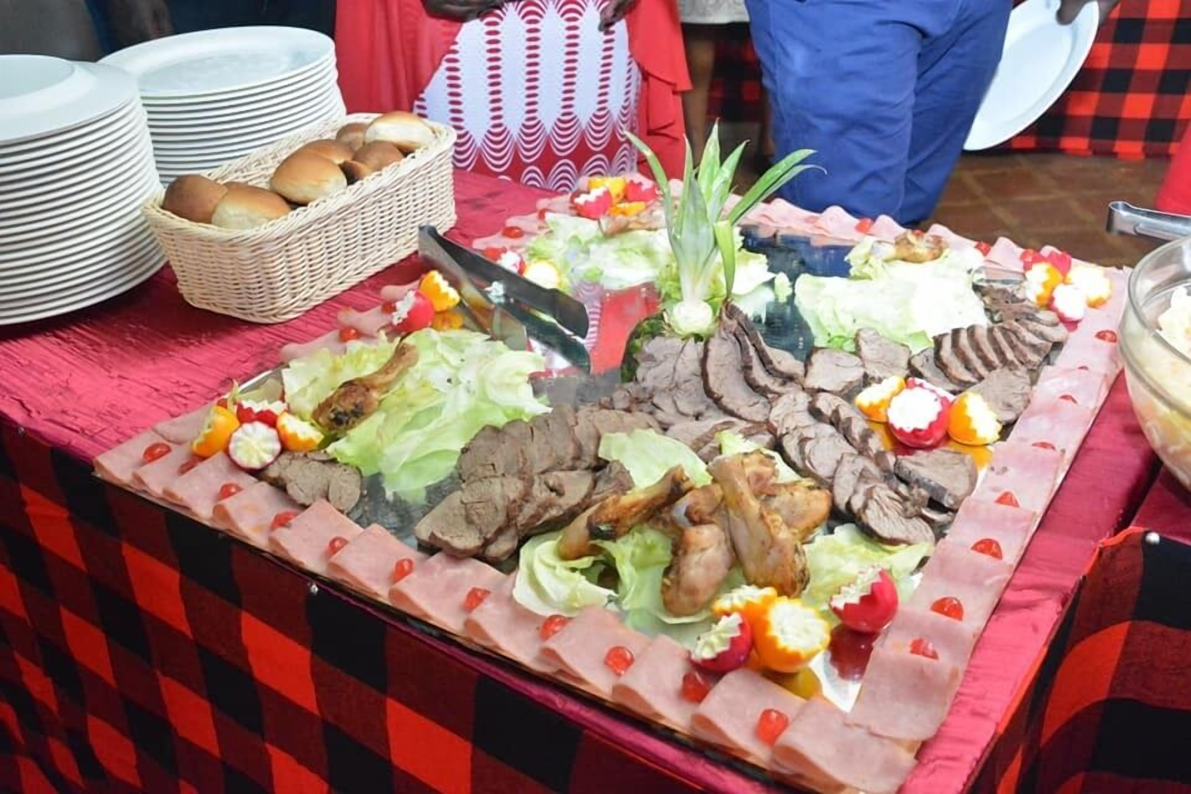 A buffet table with various meats, vegetables, and bread.